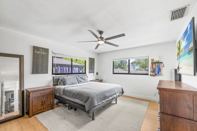 bedroom featuring light wood-type flooring, a textured ceiling, and ceiling fan