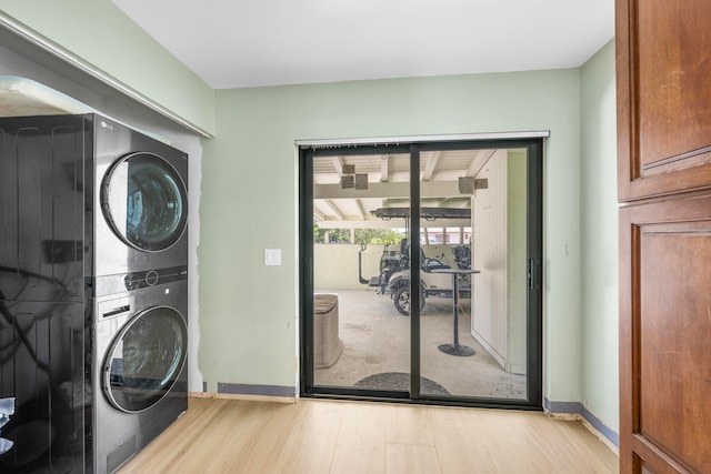 laundry room with light hardwood / wood-style flooring and stacked washing maching and dryer