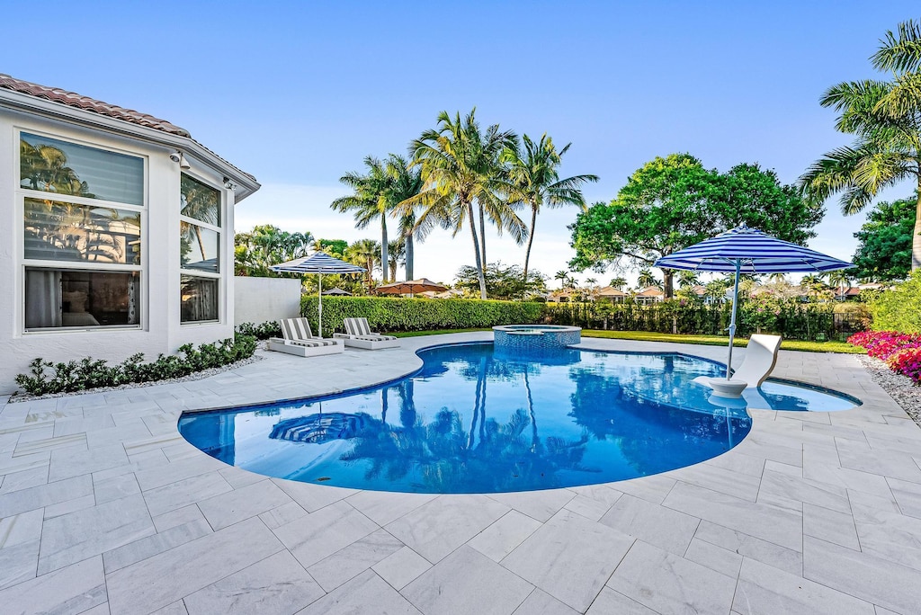 view of pool with a pool with connected hot tub, fence, and a patio