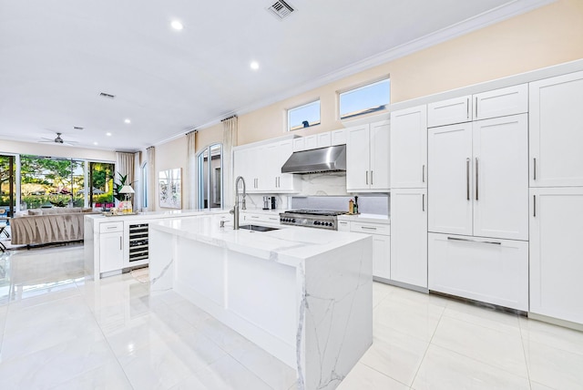 kitchen featuring white cabinets, a center island with sink, and exhaust hood