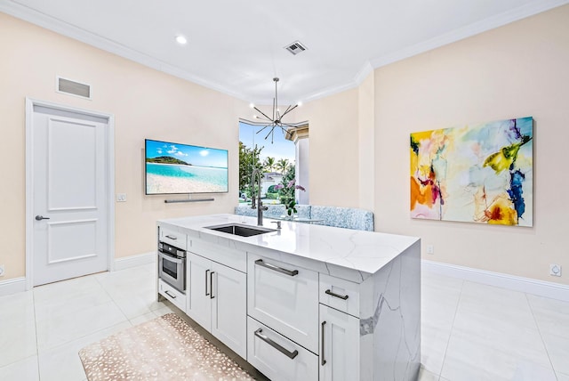 kitchen featuring light stone counters, stainless steel oven, sink, a center island with sink, and a chandelier