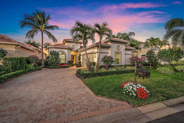 mediterranean / spanish-style home featuring a garage and a yard