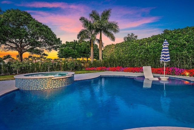 pool at dusk with an in ground hot tub