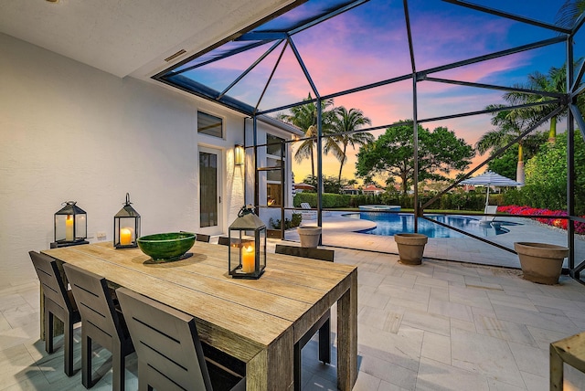 patio terrace at dusk featuring a swimming pool with hot tub and a lanai