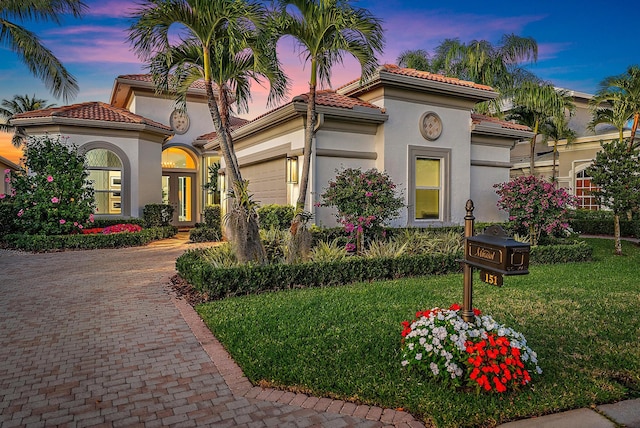 mediterranean / spanish house featuring a garage and a yard