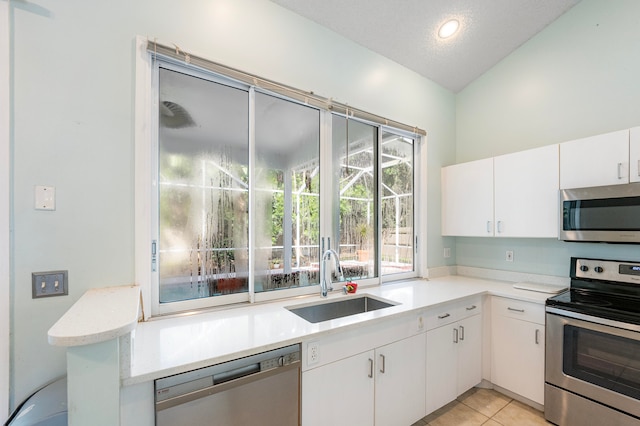 kitchen with white cabinets, appliances with stainless steel finishes, sink, and vaulted ceiling