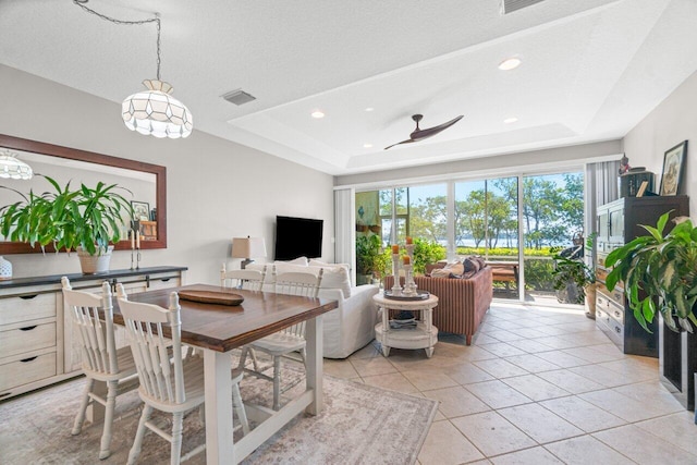 tiled living room featuring a textured ceiling, ceiling fan, and a tray ceiling