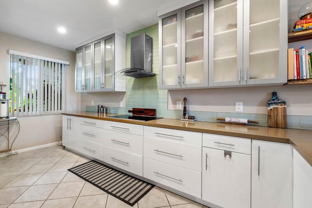 kitchen featuring light tile patterned floors, black electric cooktop, and wall chimney exhaust hood