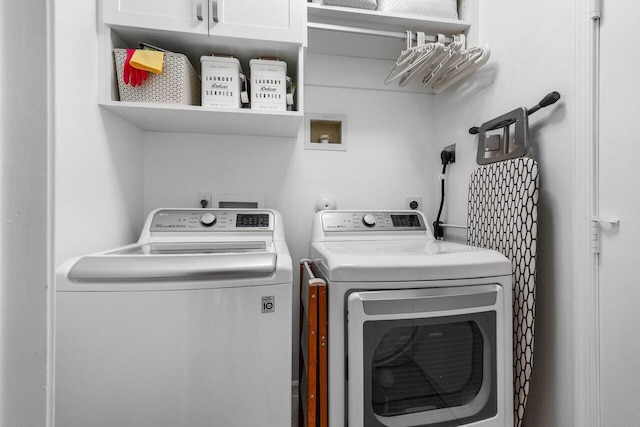 clothes washing area featuring cabinets and washing machine and dryer