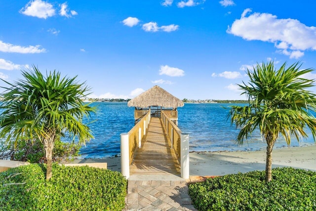 view of dock with a water view and a beach view