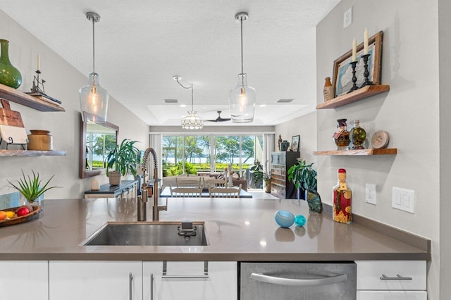 kitchen featuring white cabinetry, a tray ceiling, sink, and decorative light fixtures