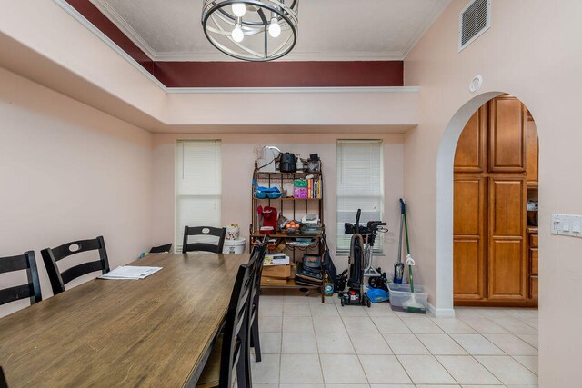 tiled dining area with ornamental molding and a notable chandelier