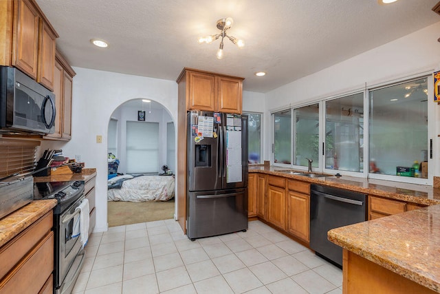 kitchen featuring light stone counters, sink, a textured ceiling, appliances with stainless steel finishes, and a notable chandelier