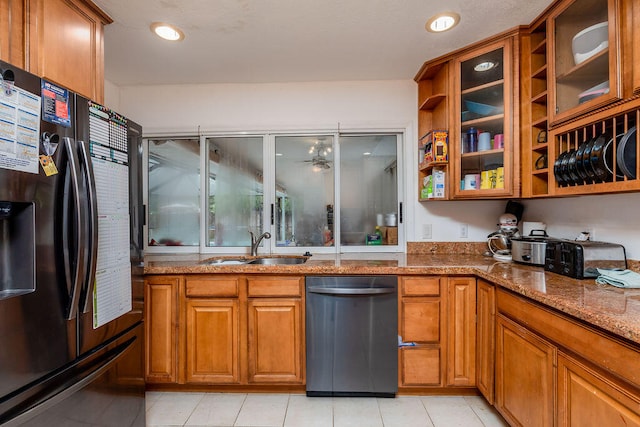 kitchen with dishwasher, light stone counters, sink, black fridge with ice dispenser, and light tile patterned floors