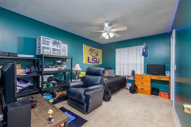 bedroom with ceiling fan, carpet flooring, and a textured ceiling