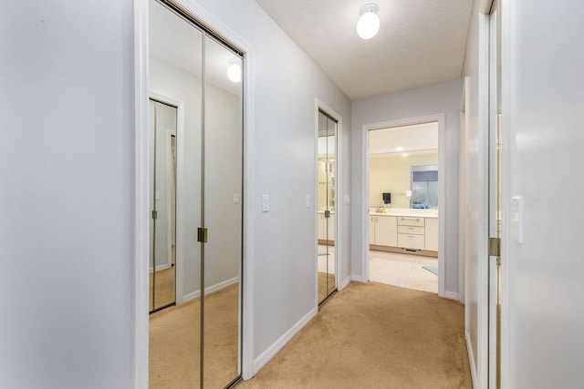 corridor featuring light carpet and a textured ceiling