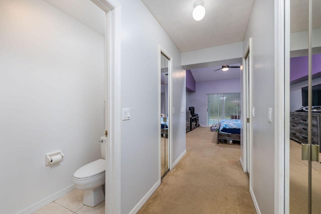 hall with light carpet and a textured ceiling