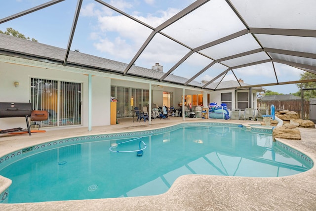 view of swimming pool featuring a patio, a grill, and a lanai