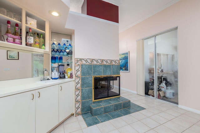 living room with light tile patterned flooring, crown molding, sink, and a tile fireplace