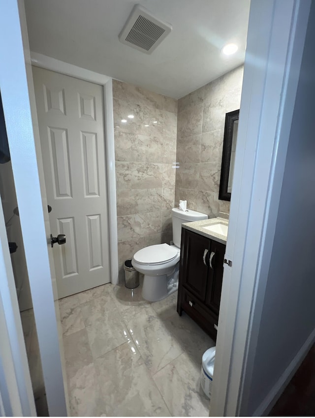 bathroom with tile walls, vanity, and toilet