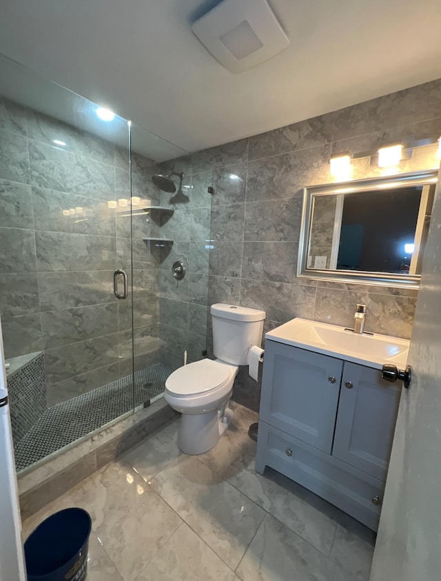 bathroom featuring toilet, vanity, tile walls, and a shower with door