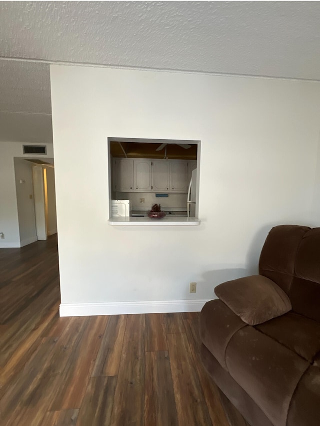 living area with dark wood-type flooring and a textured ceiling