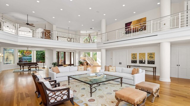 living room featuring a towering ceiling, decorative columns, and light wood-type flooring