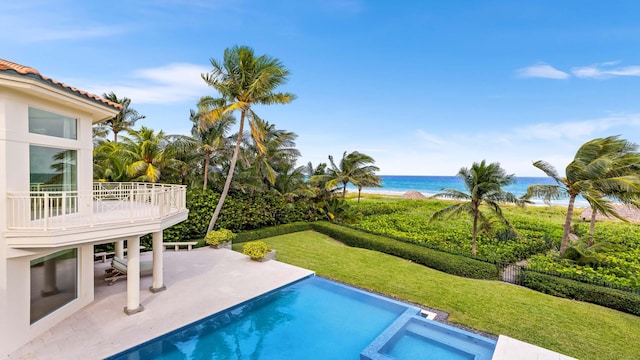 view of swimming pool with a lawn, a patio, and a water view