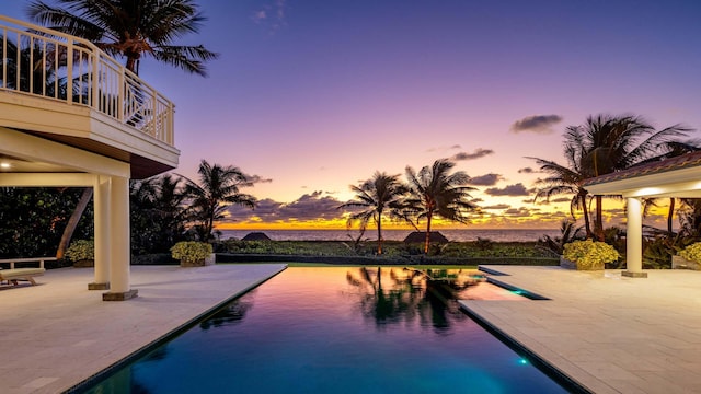 pool at dusk featuring a patio area