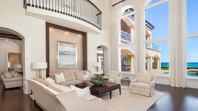 living room featuring plenty of natural light, a water view, and a high ceiling