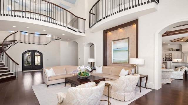 living room featuring beamed ceiling, dark hardwood / wood-style floors, a high ceiling, and french doors