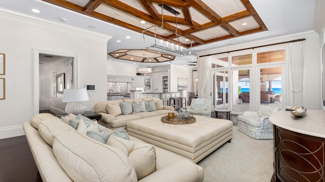 living room featuring a chandelier, beam ceiling, ornamental molding, and coffered ceiling