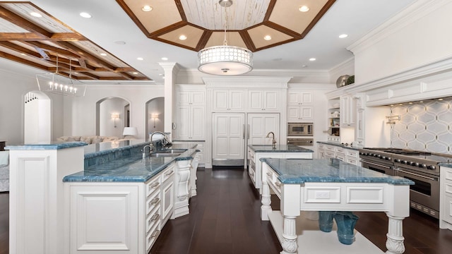 kitchen with a large island with sink, pendant lighting, stainless steel appliances, and ornamental molding