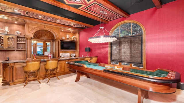 game room with beam ceiling and indoor bar