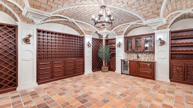 wine cellar with an inviting chandelier, wine cooler, bar, and brick ceiling