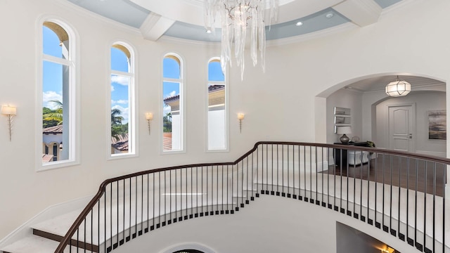 staircase with beamed ceiling, wood-type flooring, an inviting chandelier, and ornamental molding