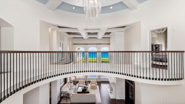 interior space with beam ceiling, coffered ceiling, an inviting chandelier, wood-type flooring, and ornamental molding