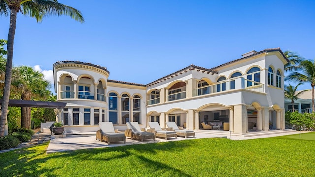 back of property featuring a patio area, a balcony, and a yard