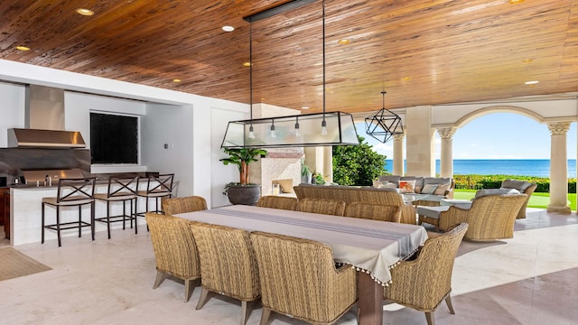 dining space featuring a water view, decorative columns, and wooden ceiling