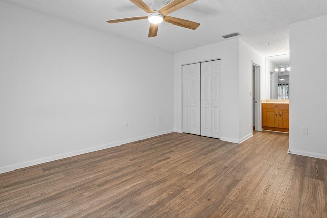 unfurnished bedroom with hardwood / wood-style flooring, ceiling fan, a textured ceiling, and a closet