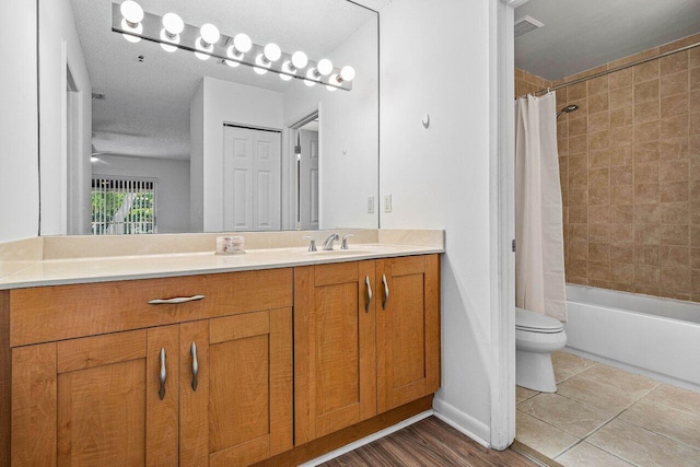 full bathroom featuring vanity, a textured ceiling, shower / tub combo with curtain, hardwood / wood-style flooring, and toilet