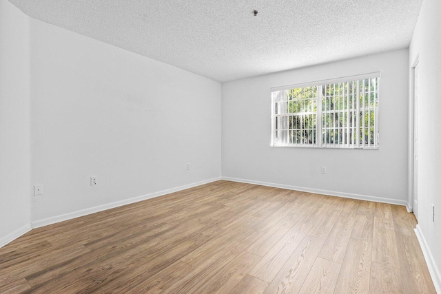 spare room featuring light hardwood / wood-style flooring and a textured ceiling