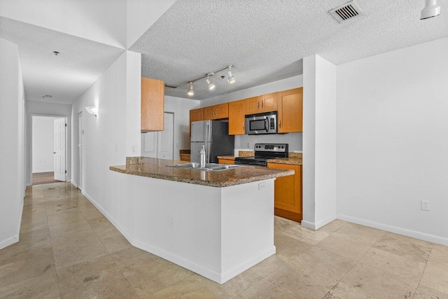 kitchen featuring dark stone counters, sink, a textured ceiling, kitchen peninsula, and stainless steel appliances