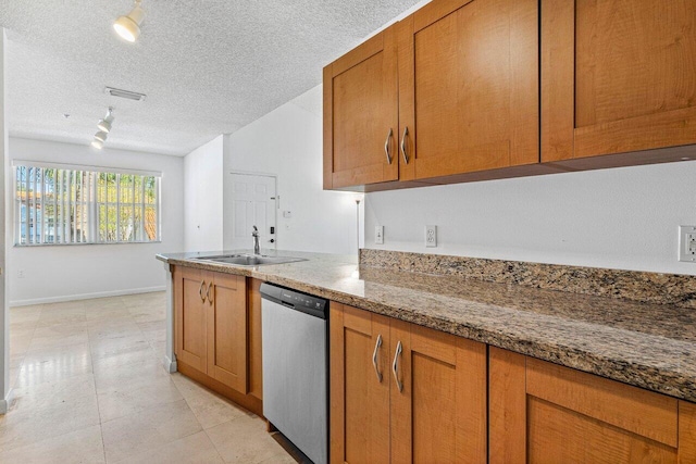 kitchen with light stone countertops, rail lighting, stainless steel dishwasher, a textured ceiling, and sink