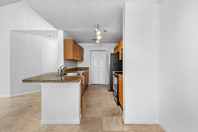 kitchen with kitchen peninsula, appliances with stainless steel finishes, a textured ceiling, and sink