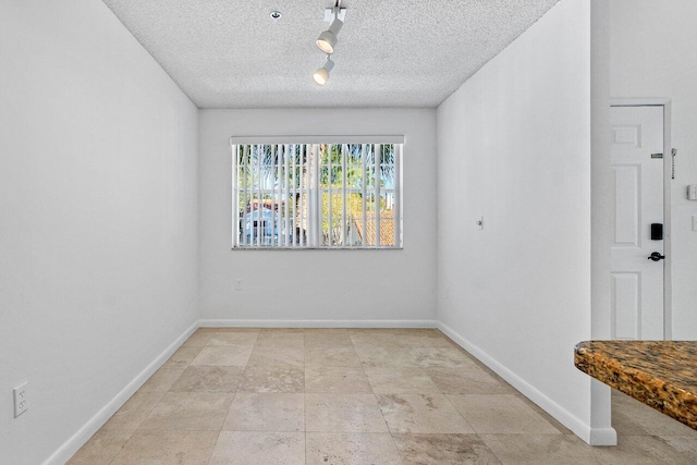 unfurnished room featuring rail lighting and a textured ceiling