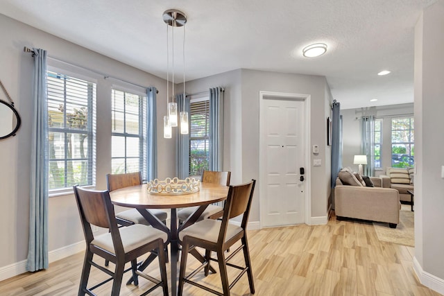 dining area with a textured ceiling and light hardwood / wood-style floors