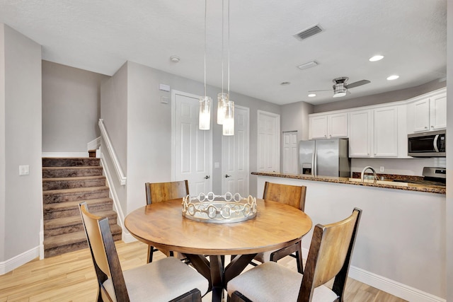 dining space with a textured ceiling, light hardwood / wood-style flooring, and ceiling fan