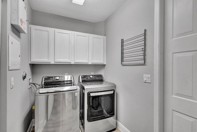 laundry area with washer and clothes dryer, cabinets, and a textured ceiling