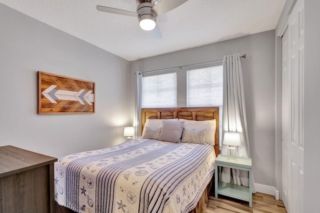 bedroom featuring a textured ceiling, light wood-type flooring, a closet, and ceiling fan